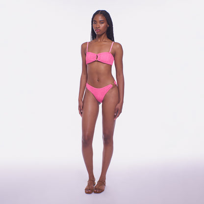 Model wearing a pink bikini set on a white background