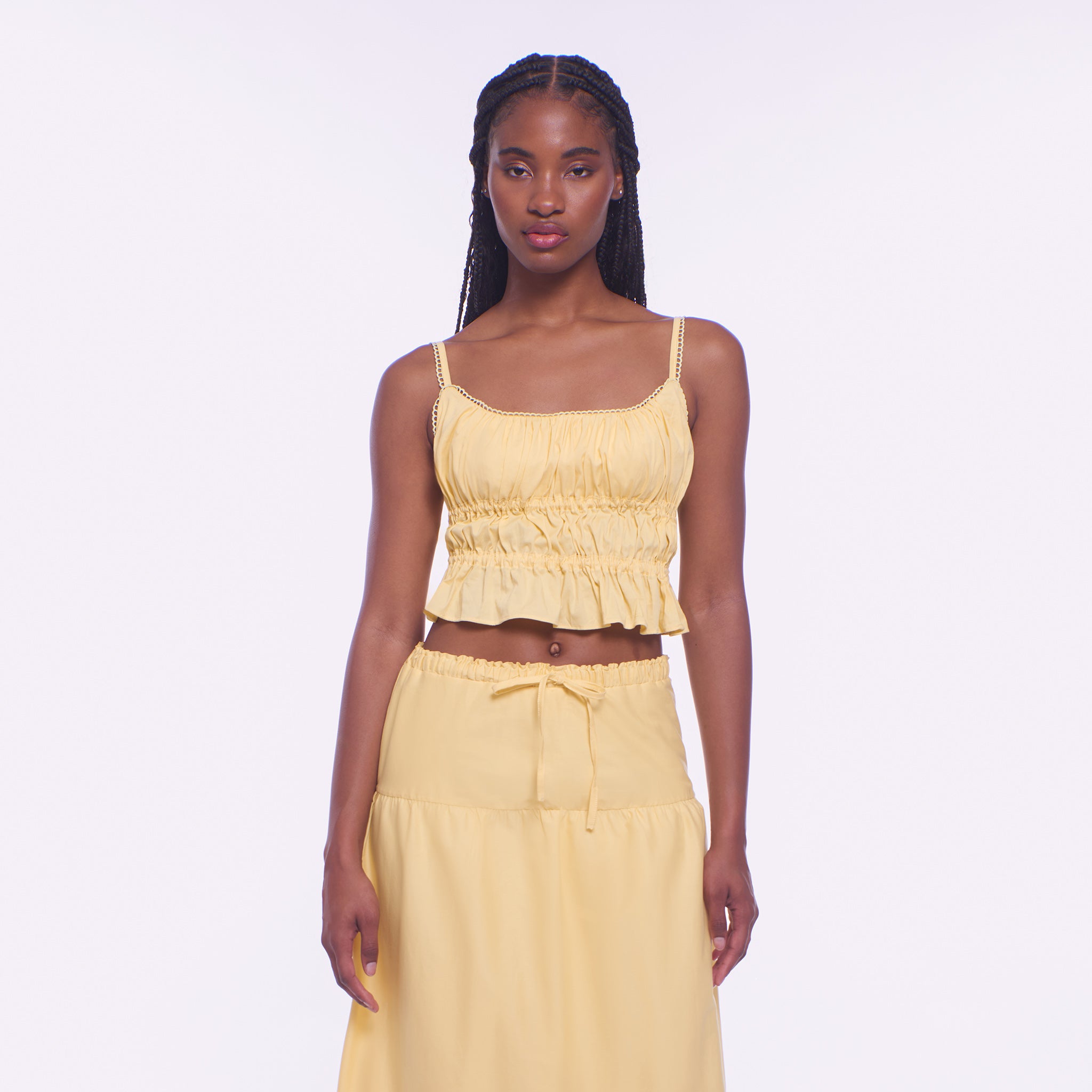 Woman wearing a yellow top and skirt set on a white background