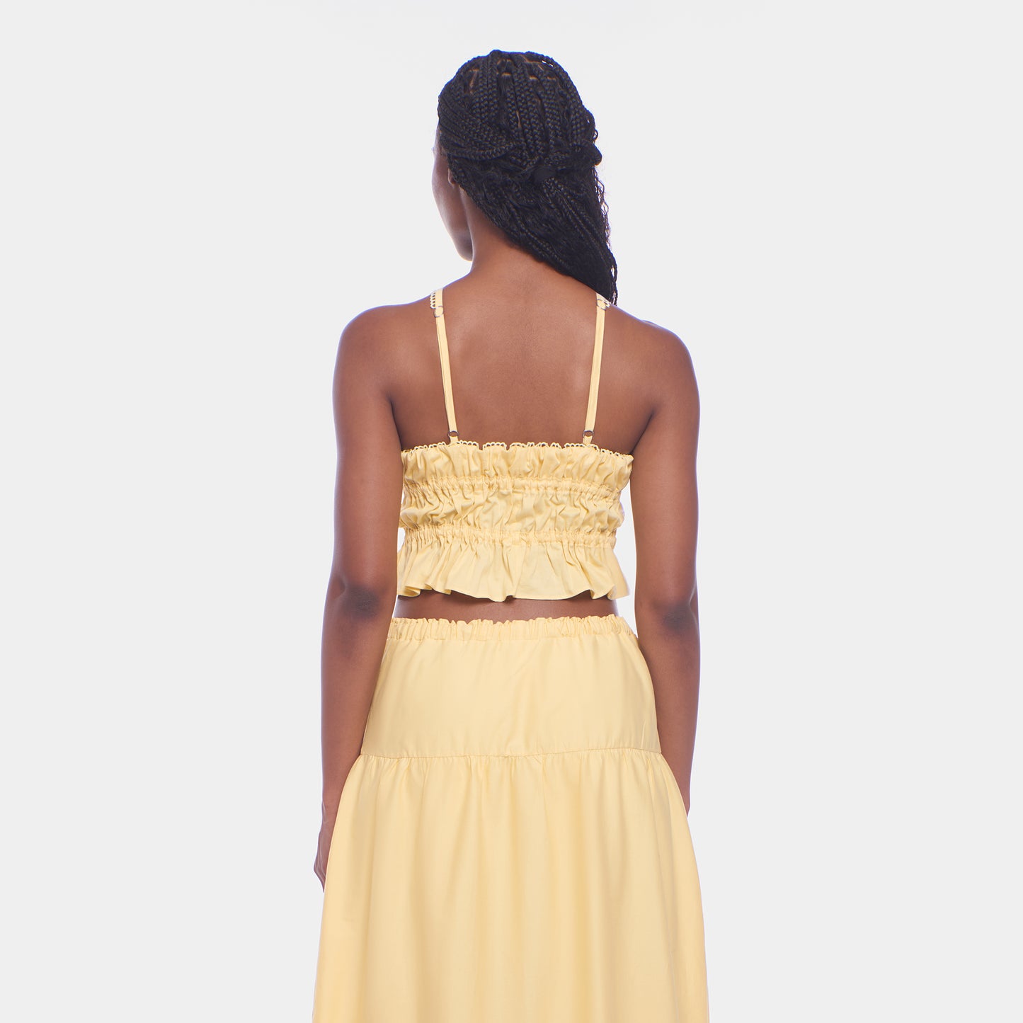Woman wearing a yellow two-piece outfit on a white background