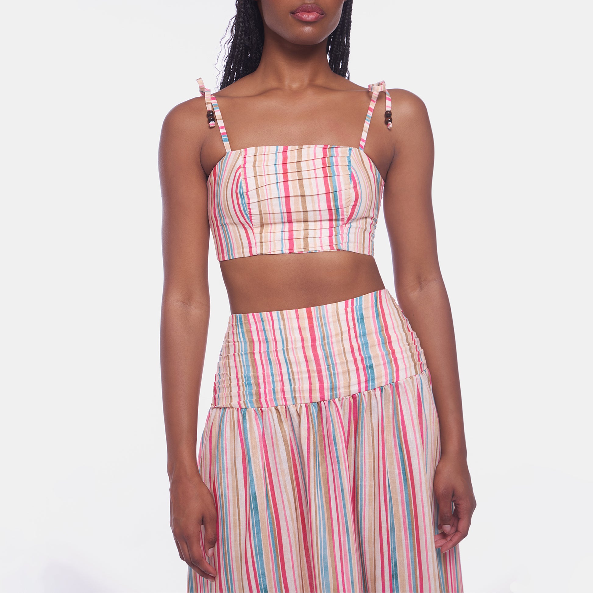 Woman wearing a colorful striped two-piece outfit on a white background