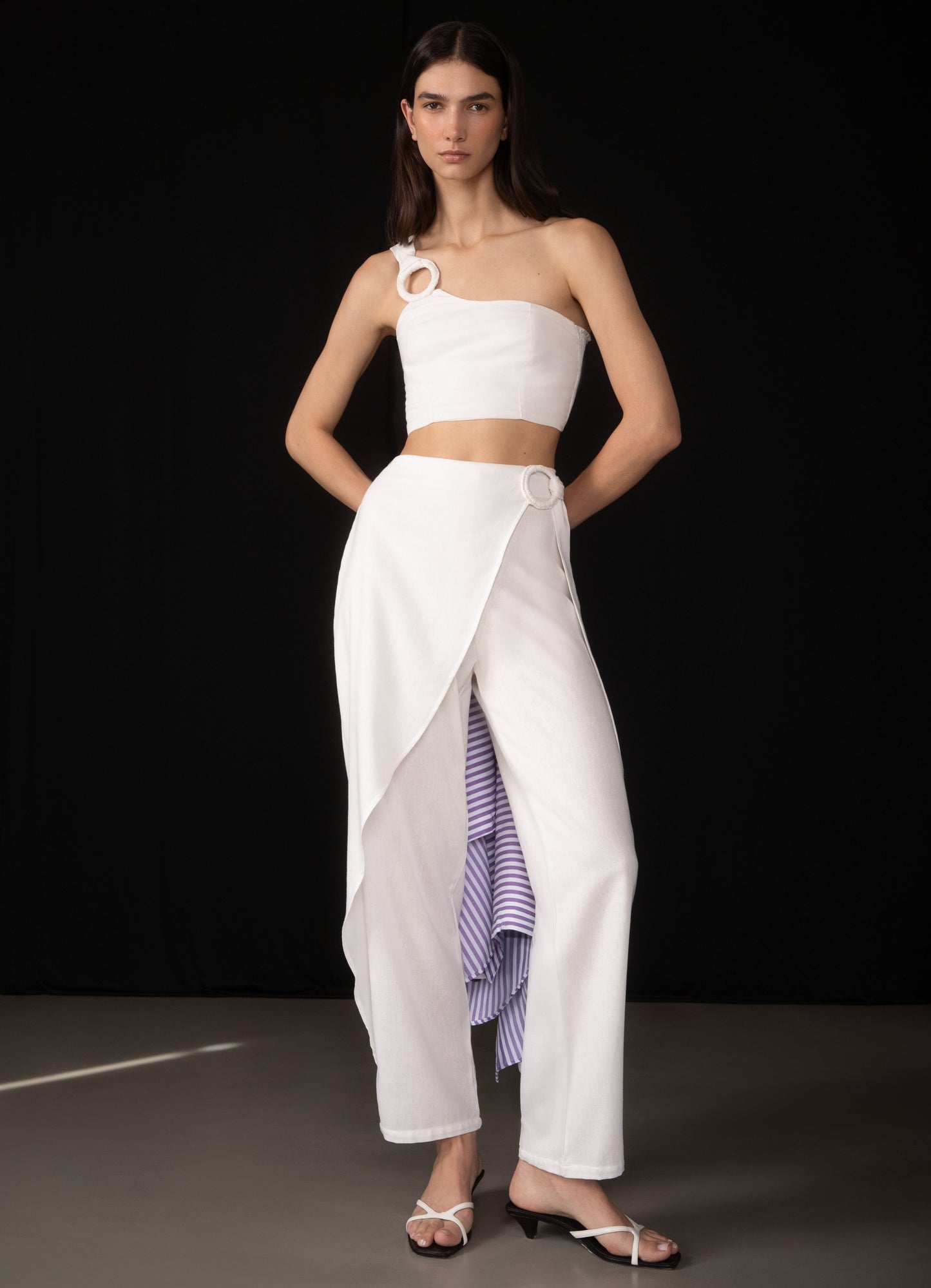 Model wearing a white outfit with a black background